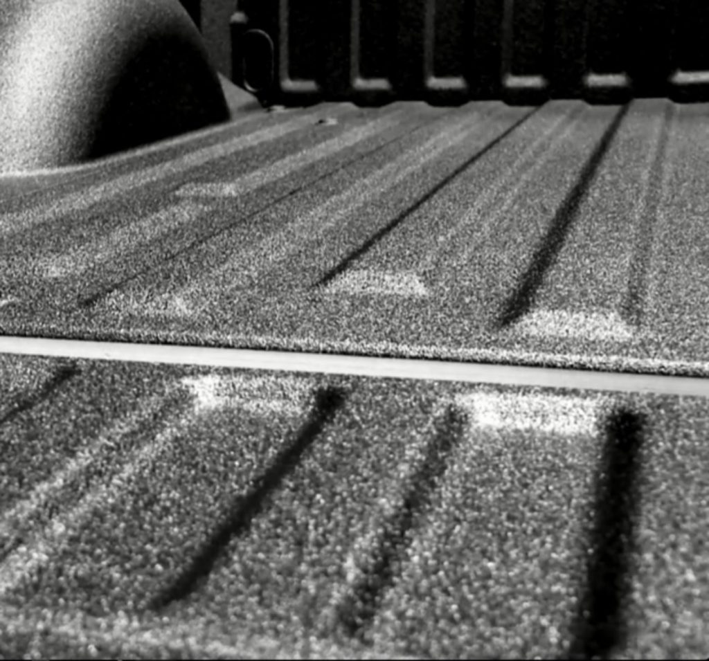 Close-up of polyurea coating on the bed of a white commercial work vehicle