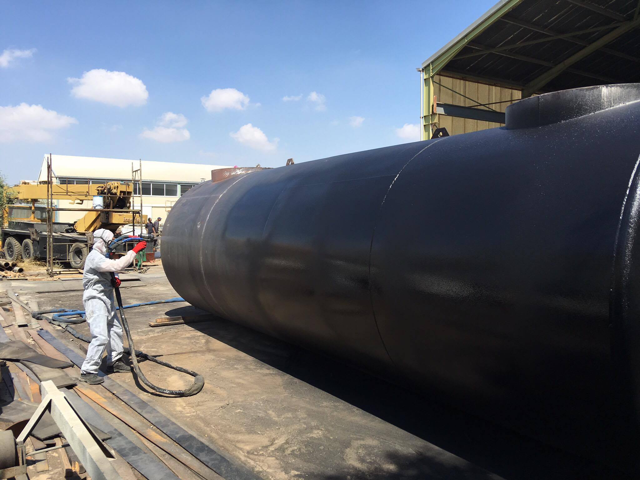 Technicians spraying polyurea coatings on an oil tank